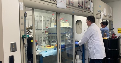 A man in a white doctor's coat is doing work in a biotech laboratory